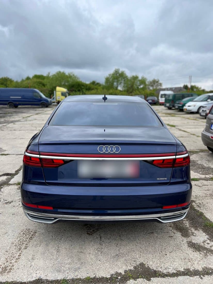 Tmavě modré Audi A8 zezadu na betonové ploše