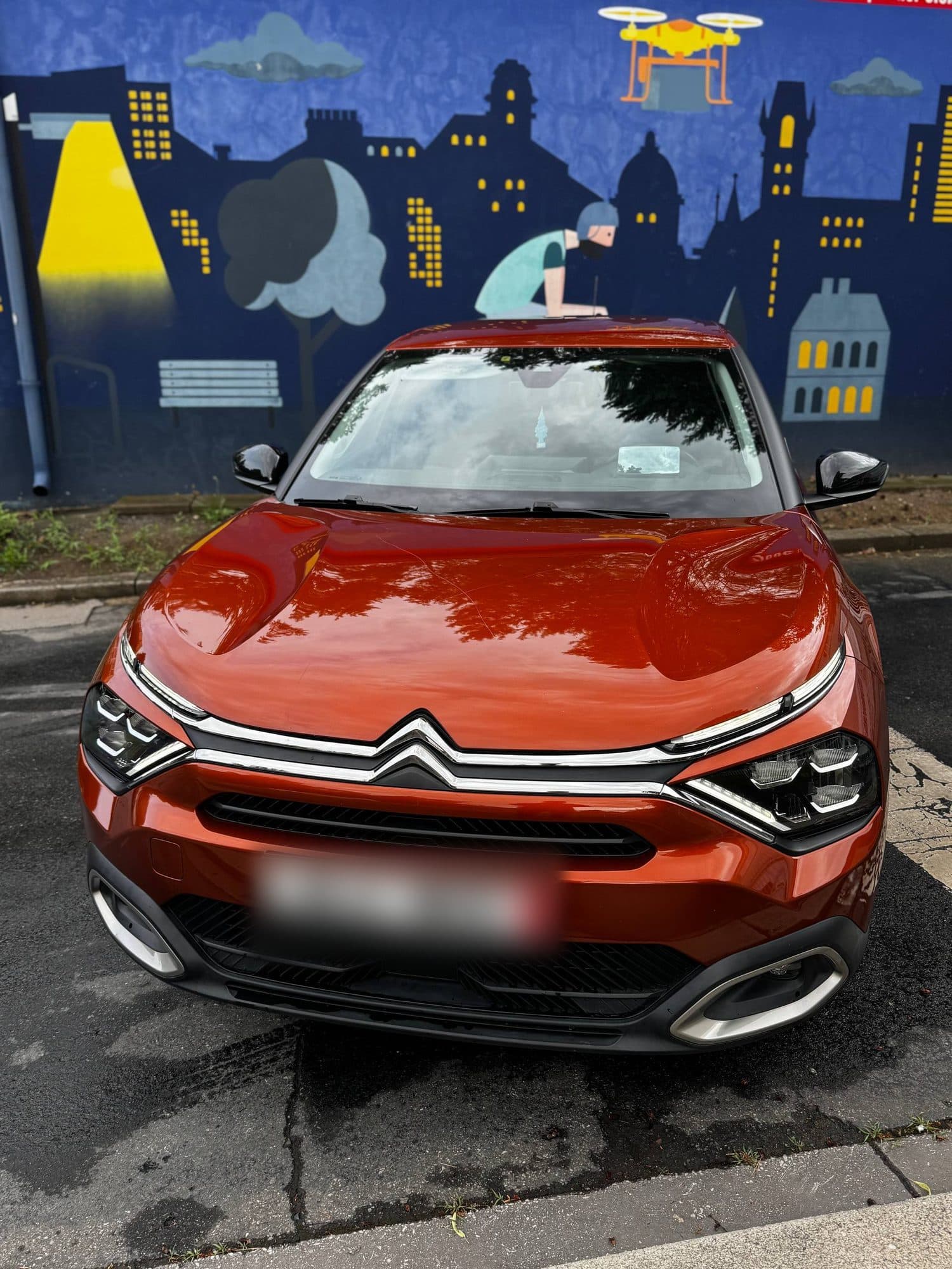 Oranžový Citroën C4 před malovanou zdí